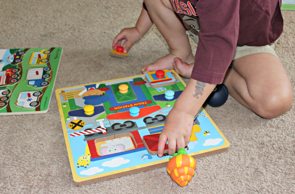 Child using peg puzzles for fine motor skills development | Fine Motor Activities for Toddlers and Preschoolers from livewellplaytogether.com