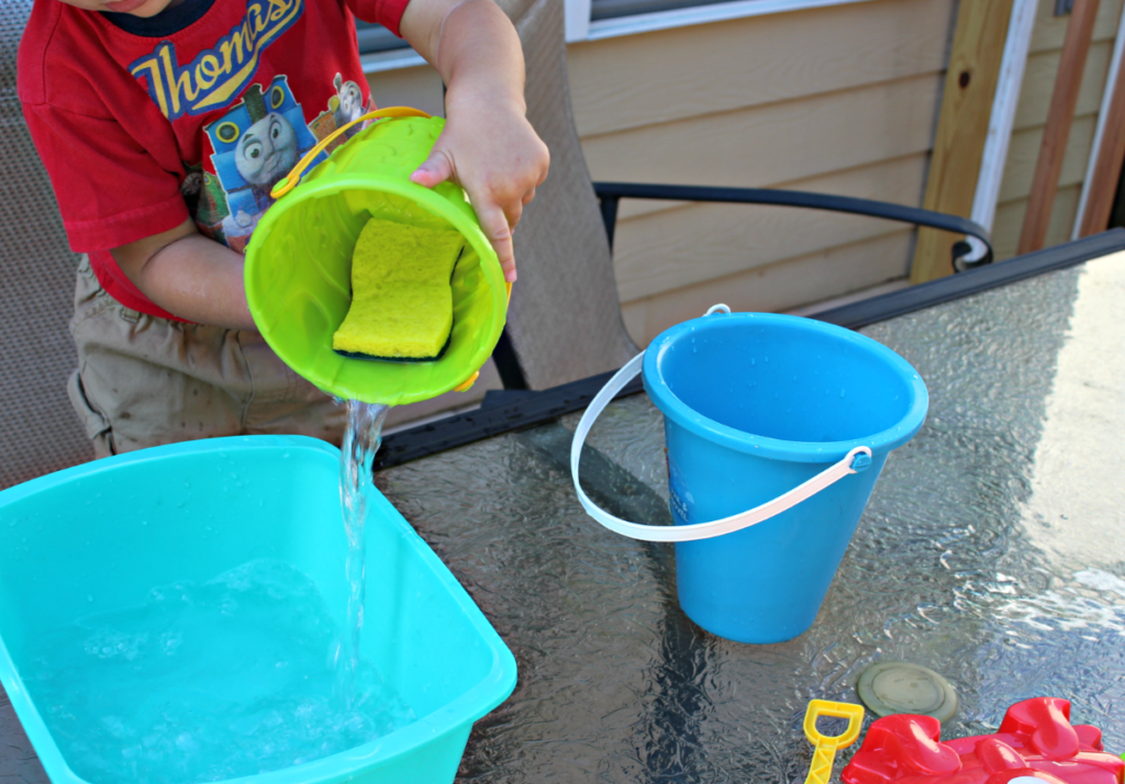 This fun water transfer activity is easy to set up and fun to play. Great water play and sensory play activity for kids. Plus extra questions for additional learning opportunities. This is an excellent way to encourage the development of motor skills and spatial awareness as children see how much water can fit into each container. #playbasedlearning #homeschool #preschool #toddleractivites #stemlearning #stemforkids #waterplay #sensorybins #scienceforkids