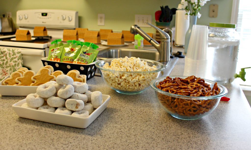 Gingerbread House Decorating Party - Christmas Party Snack Menu - Sugar cookies, powdered donuts, popcorn, and pretzels on the counter