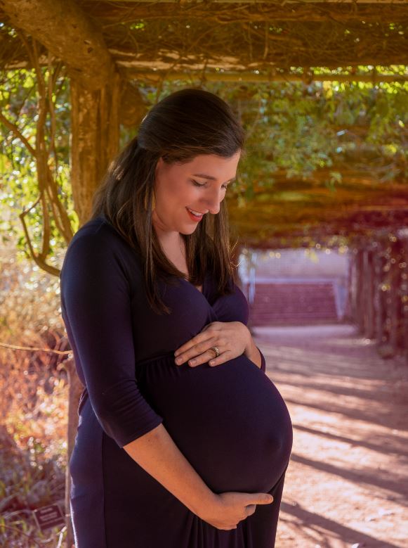 Mother holding pregnant belly during 3rd trimester. 33 Weeks Pregnant Update with Baby #3! Outdoor Maternity Photography by Andre Watson Photography.