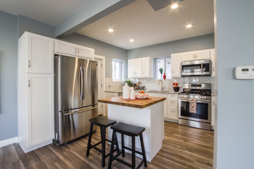 Family Kitchen with white cabinets and stainless steel appliances. This post is about the benefits of decluttering your home. Learn why you should declutter your home today. 