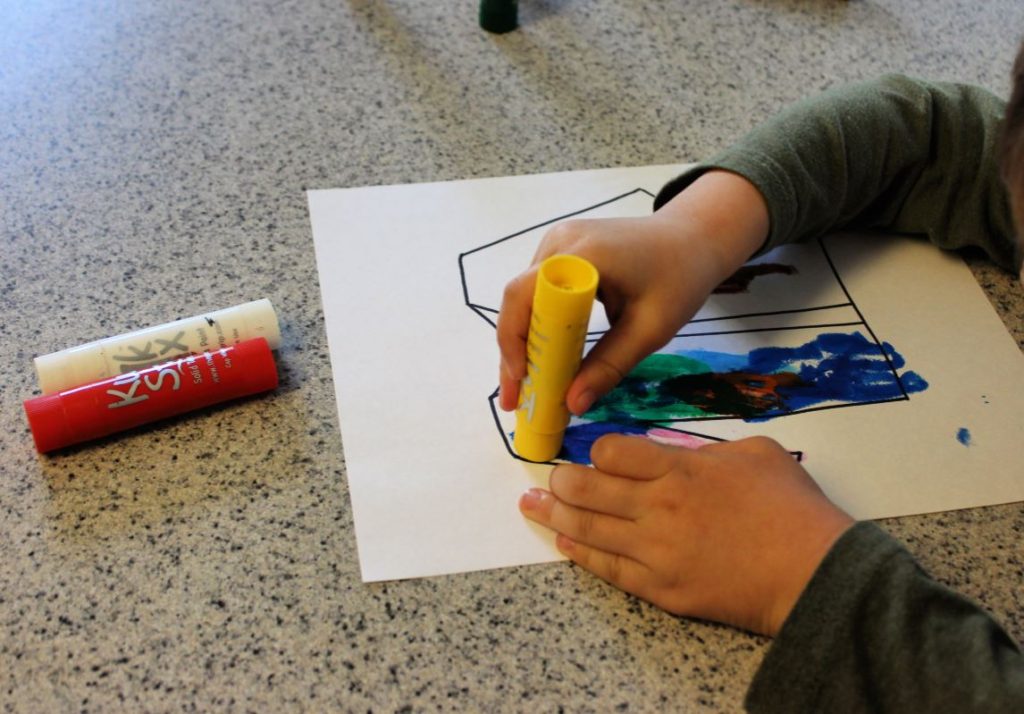 Preschooler using paint sticks to complete a Bible craft for Joseph's coat of many colors