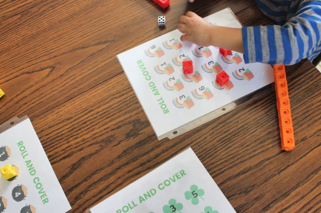 Preschooler playing roll and cover game to practice number recognition