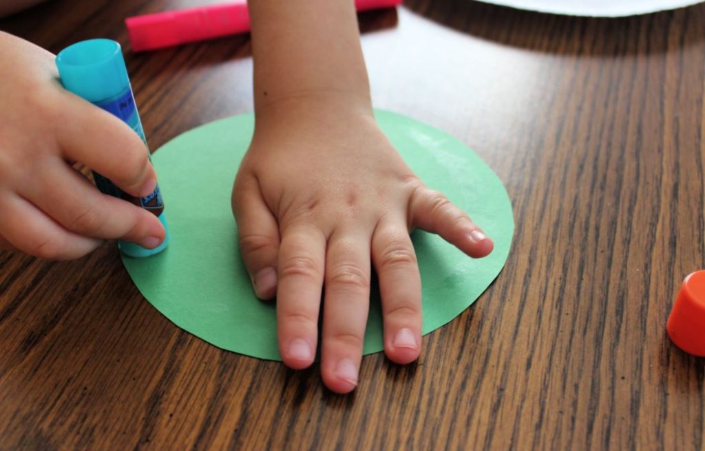 Toddler hands using a glue stick for arts and crafts