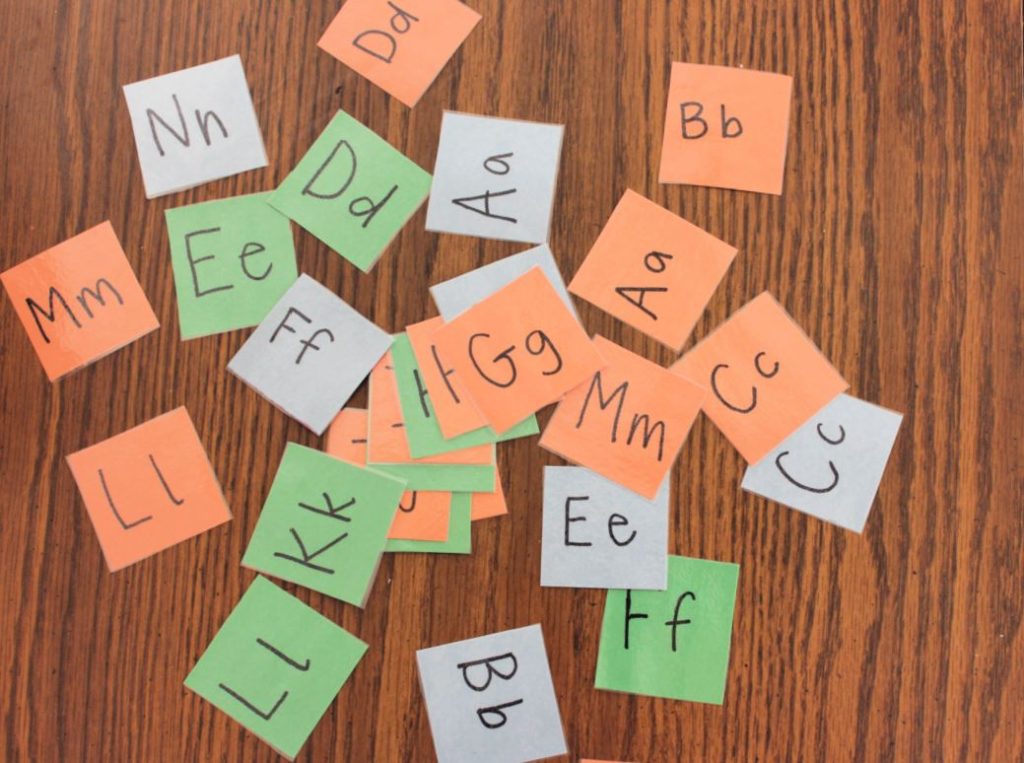 Colorful ABC flashcards scattered on a table to play an alphabet memory game. 