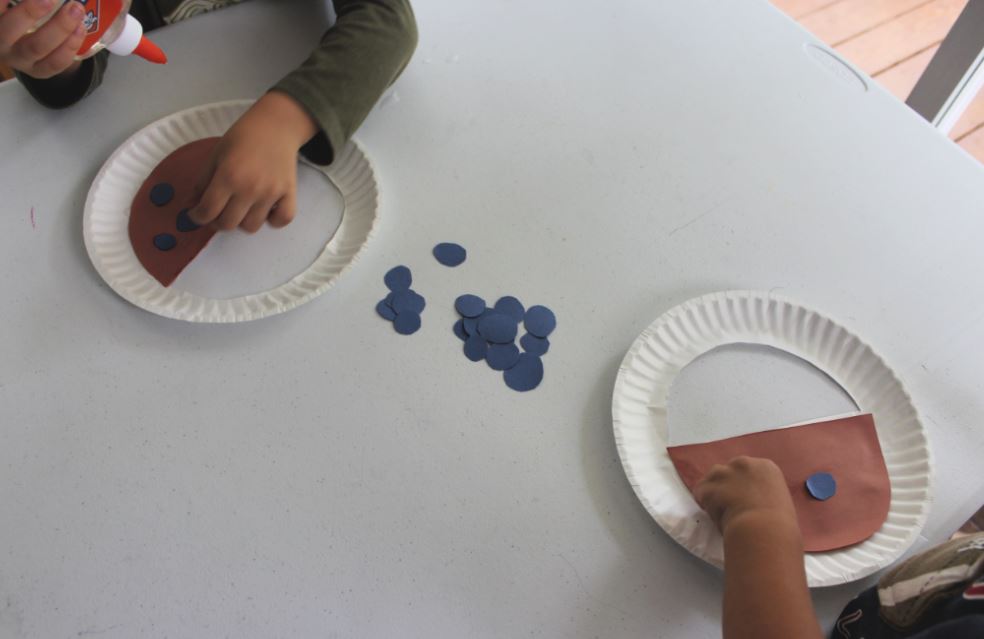 Blueberries for Sal Paper Plate activity. Kids gluing construction paper blueberries to paper plate pails.