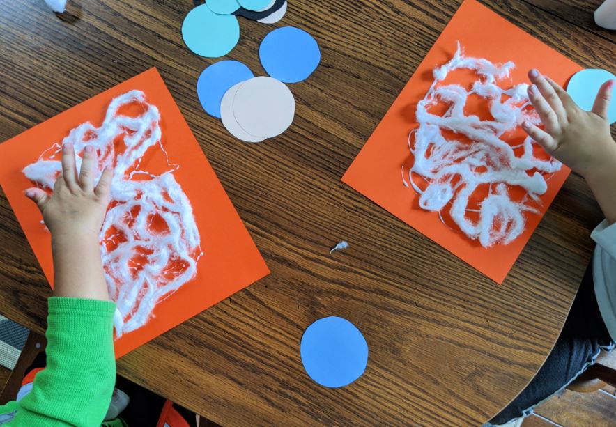 Children making a spider web out of cotton balls. A fun spider craft idea for preschoolers