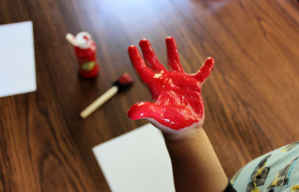 Toddler hand painted red to make a handprint apple craft
